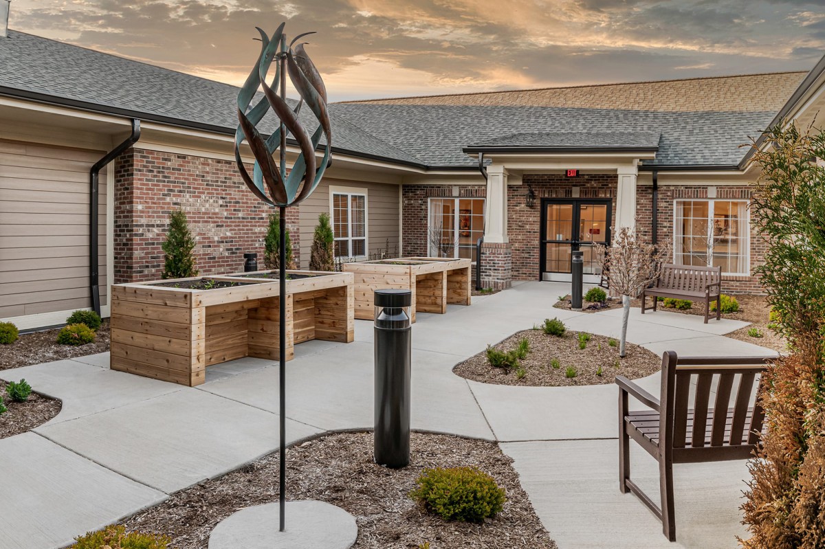 A modern courtyard featuring a contemporary sculpture and neatly arranged landscaping.