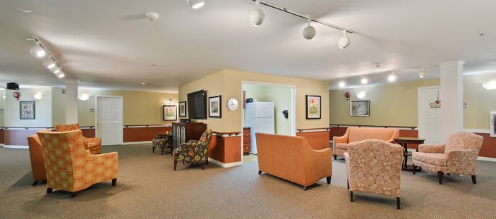 A cozy living room with sofas, armchairs, and a television set.