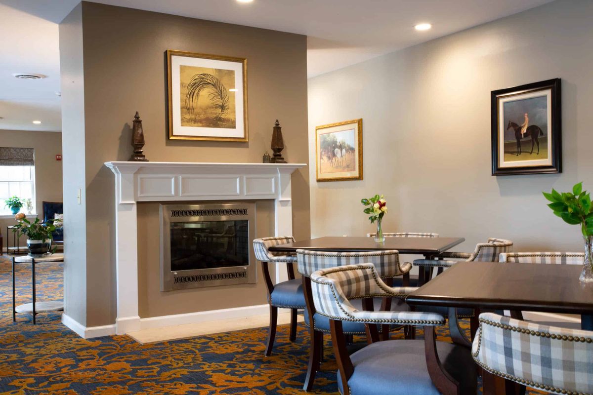 A cozy dining area with tables, chairs, and a fireplace adorned with artwork.