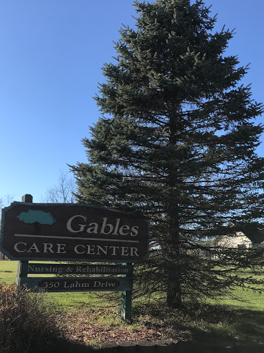 The Gables Care Center sign displayed against a backdrop of a tall tree and clear blue sky.