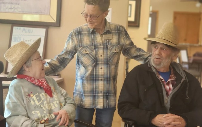 A supportive interaction between three people, two of whom are sitting in wheelchairs, indoors.