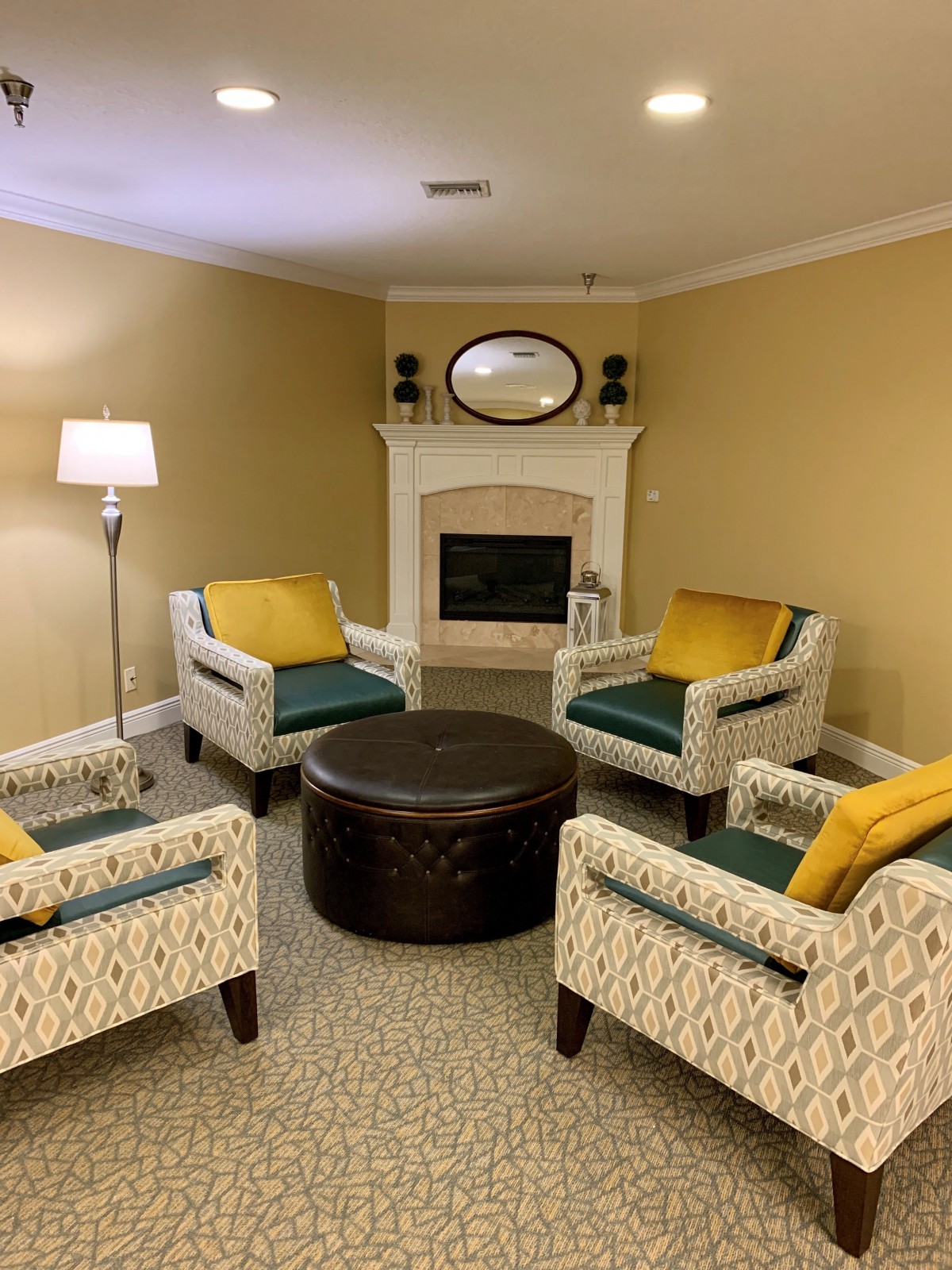 A cozy living room with four patterned chairs, a round coffee table, and a fireplace with decorative accents.