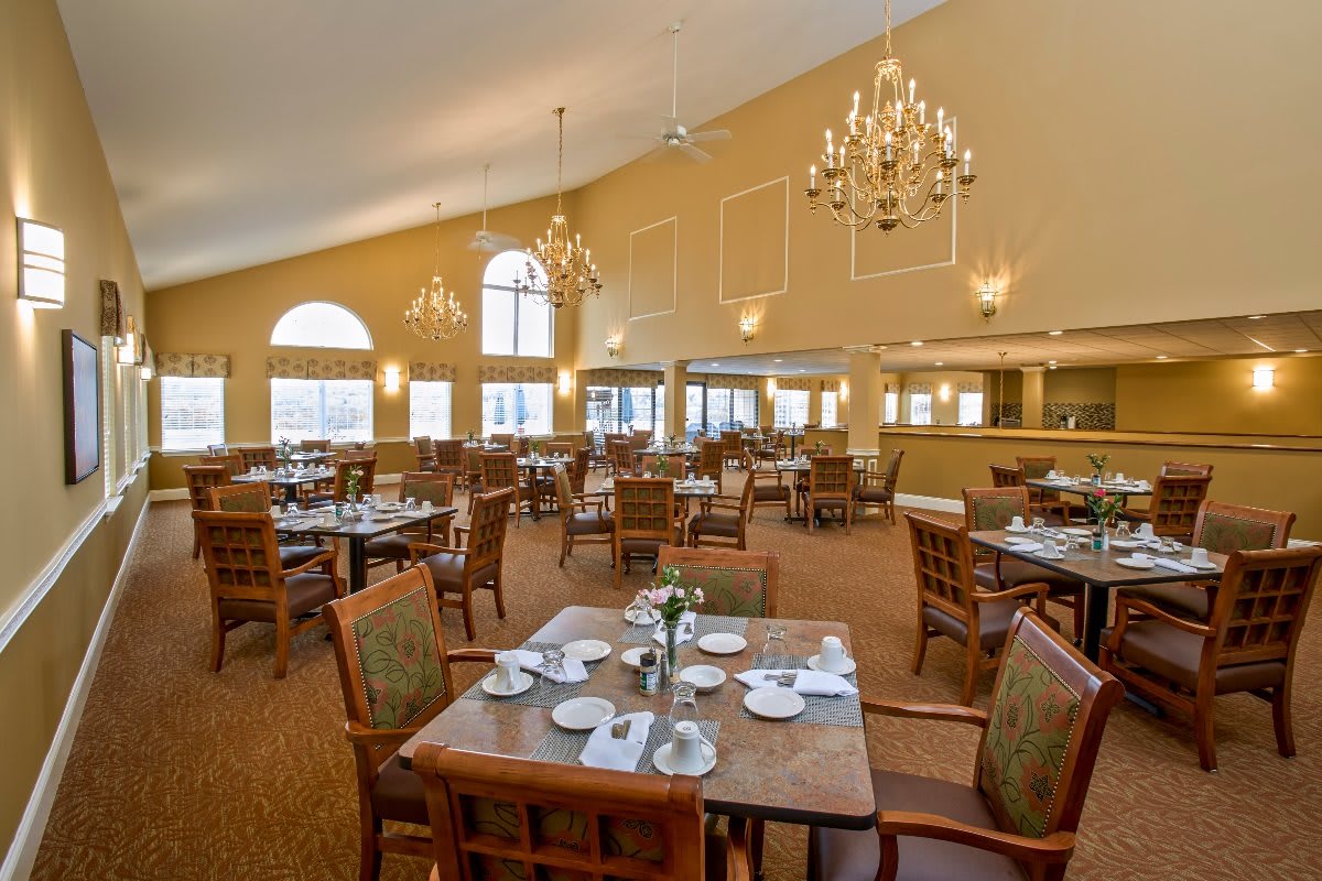 A spacious dining room with elegantly set tables and chandeliers.