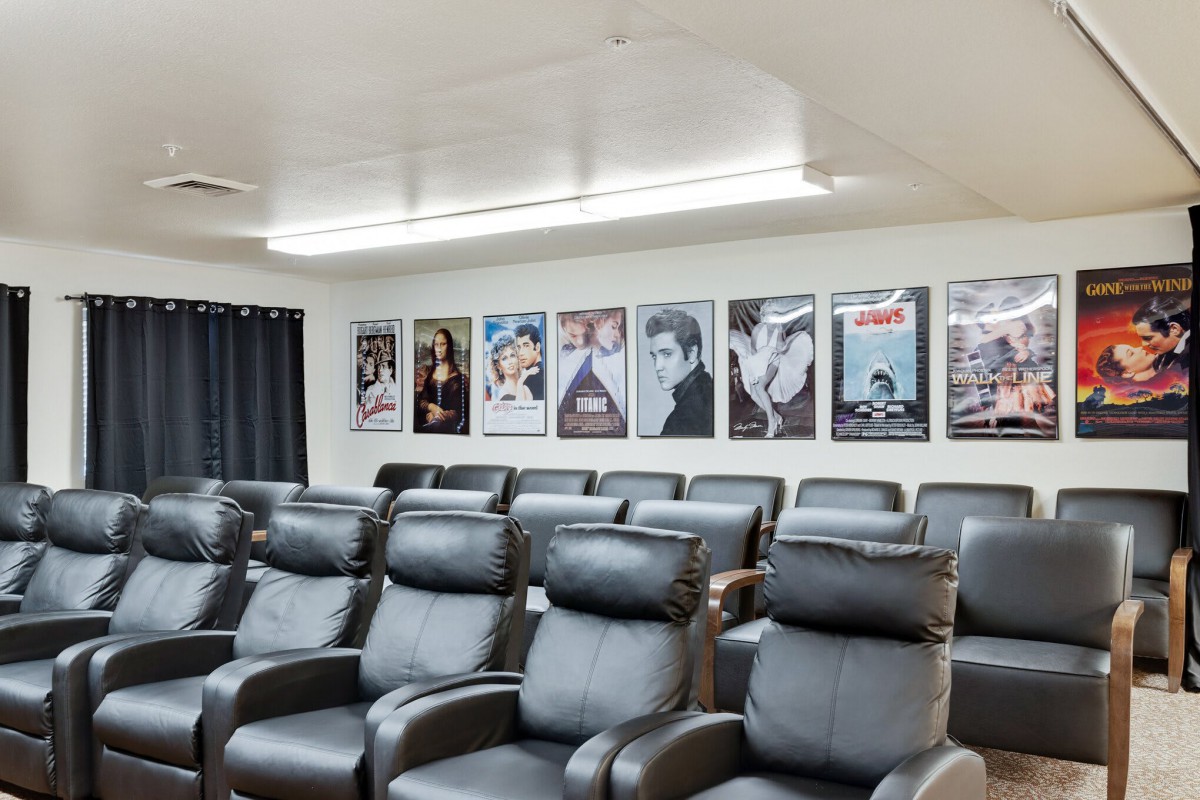 A cozy home theater setup with a row of plush recliner chairs facing a wall adorned with classic movie posters.