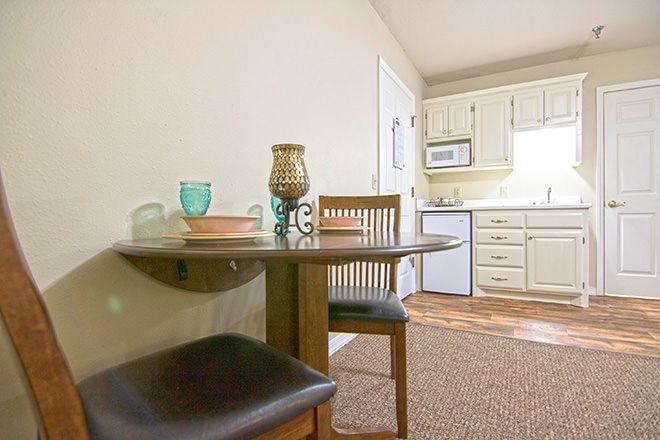 A cozy dining area adjacent to a compact kitchen, featuring modern decor and wooden furniture.