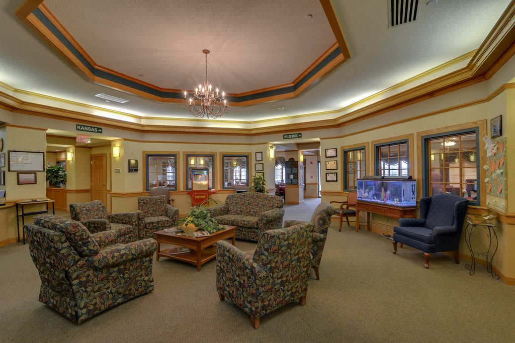 A cozy lobby area featuring a central seating arrangement with comfortable chairs, a chandelier, and a fish tank for ambiance.