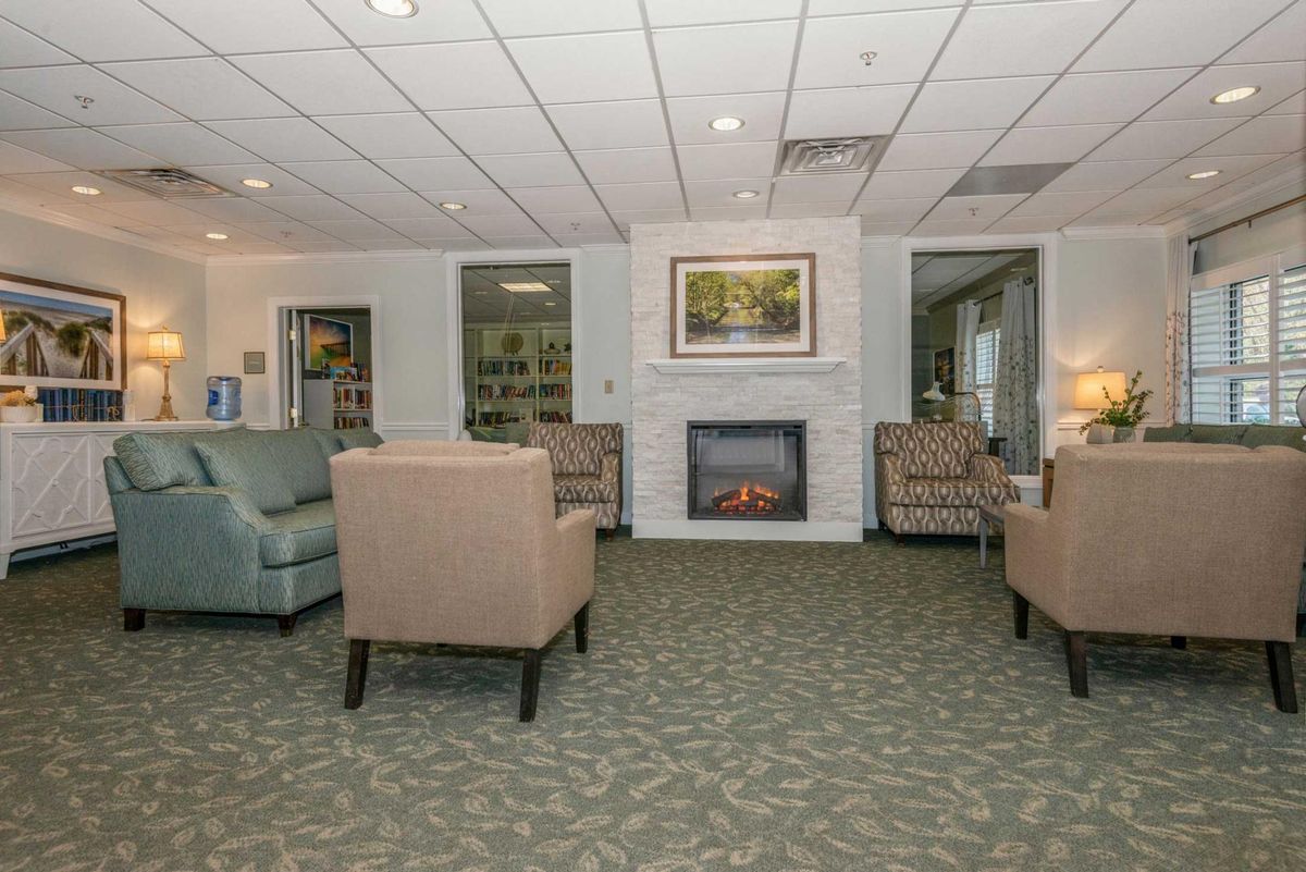 A cozy living room with armchairs, a fireplace, and a carpeted floor.