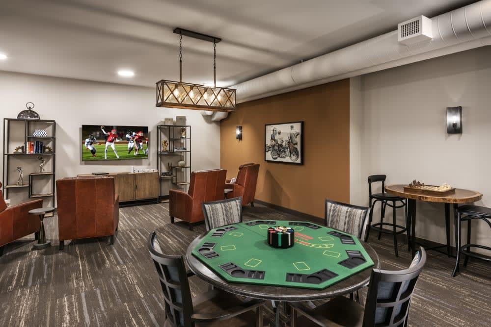 A stylish game room featuring a poker table, comfortable seating, and a television for entertainment.