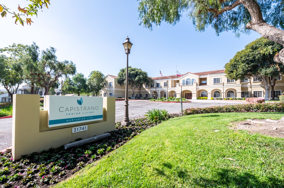 A view of a landscaped area with a building and sign in the background.