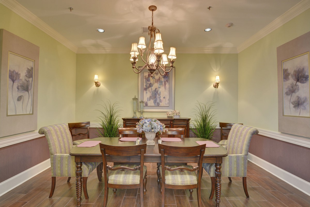 An elegantly designed dining room featuring a wooden table, upholstered chairs, a chandelier, and tasteful decor.