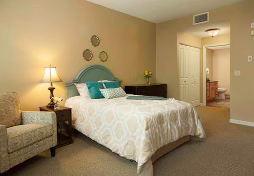 A cozy bedroom featuring a neatly made bed, a decorative lamp, and tasteful wall decor.