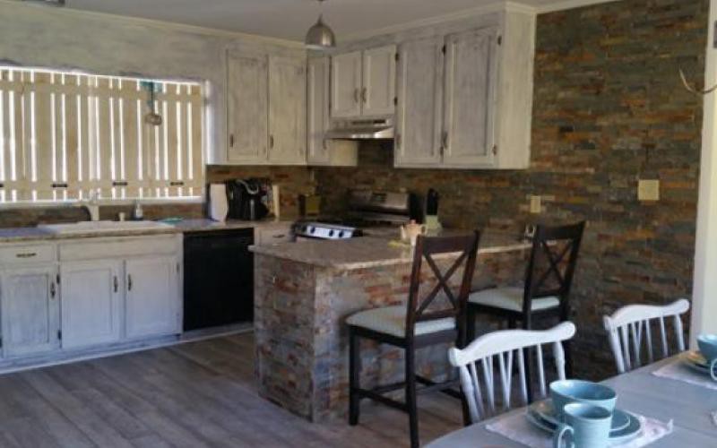 A cozy kitchen featuring stone accents, modern appliances, and bar seating.