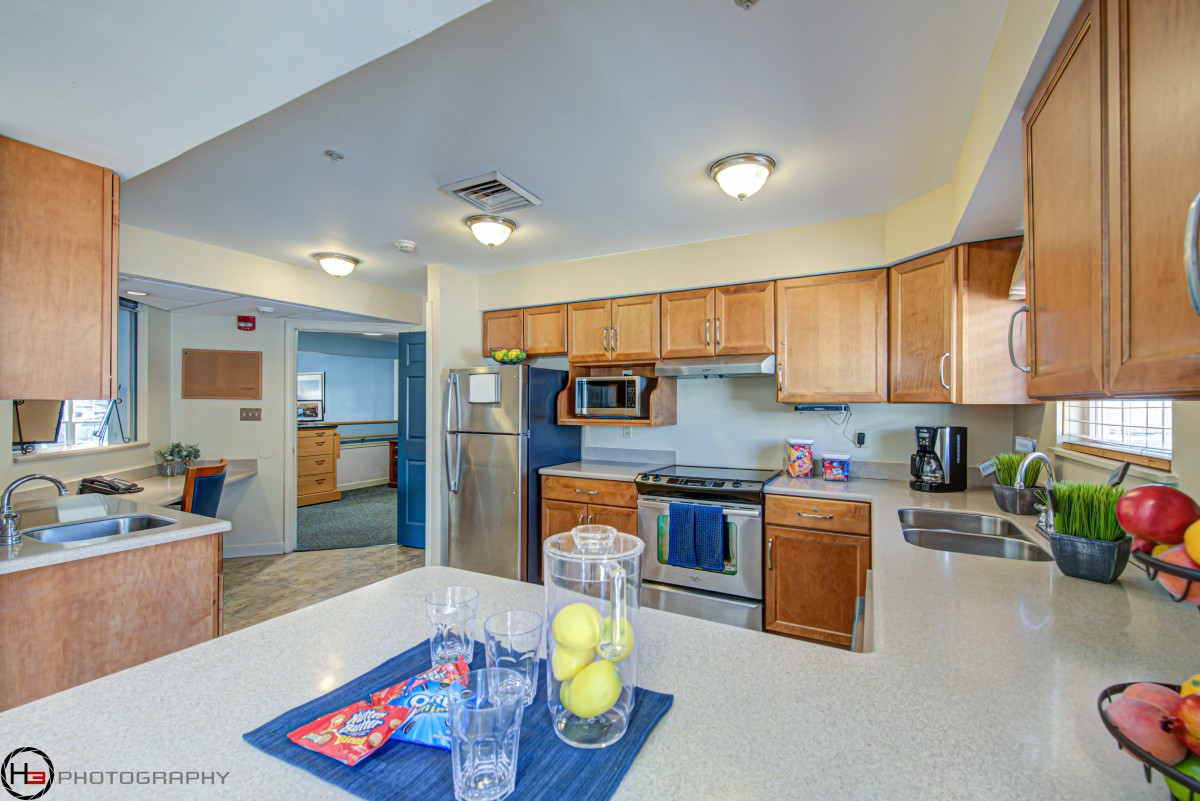 A modern kitchen with wooden cabinets, featuring stainless steel appliances and a spacious island countertop.