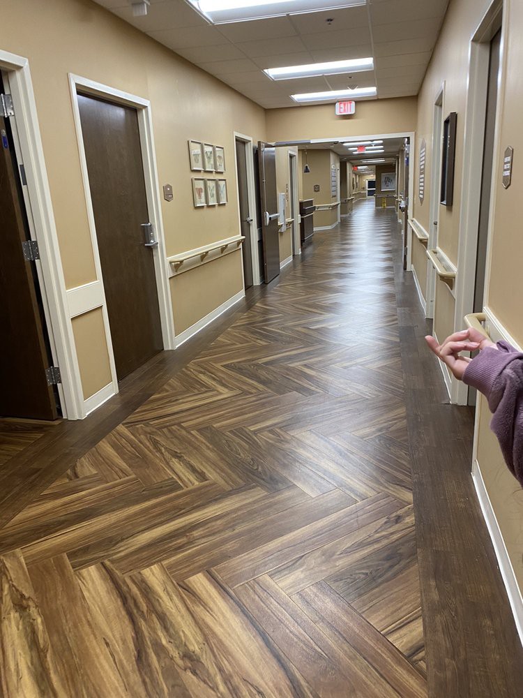 A long, well-lit hallway with wooden flooring and multiple doors on either side.