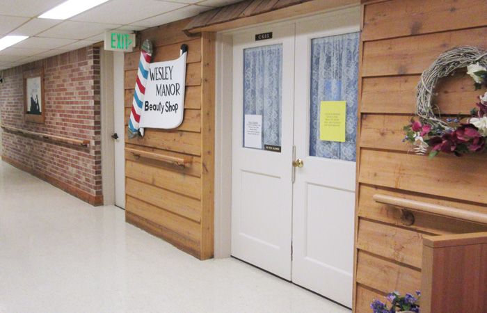 Entrance to a barber shop with wooden paneling and double white doors in a corridor.