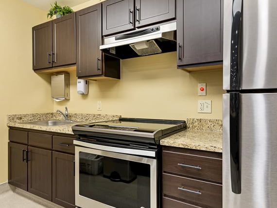 A modern kitchen with dark cabinets, stainless steel appliances, and granite countertops.