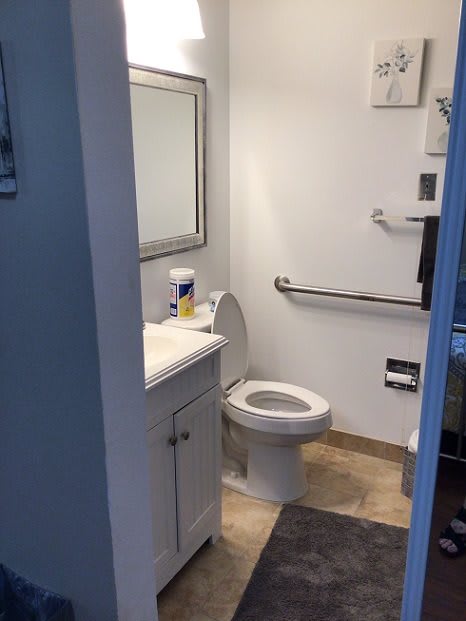 A small bathroom with a toilet, sink, mirror, and towel rack.