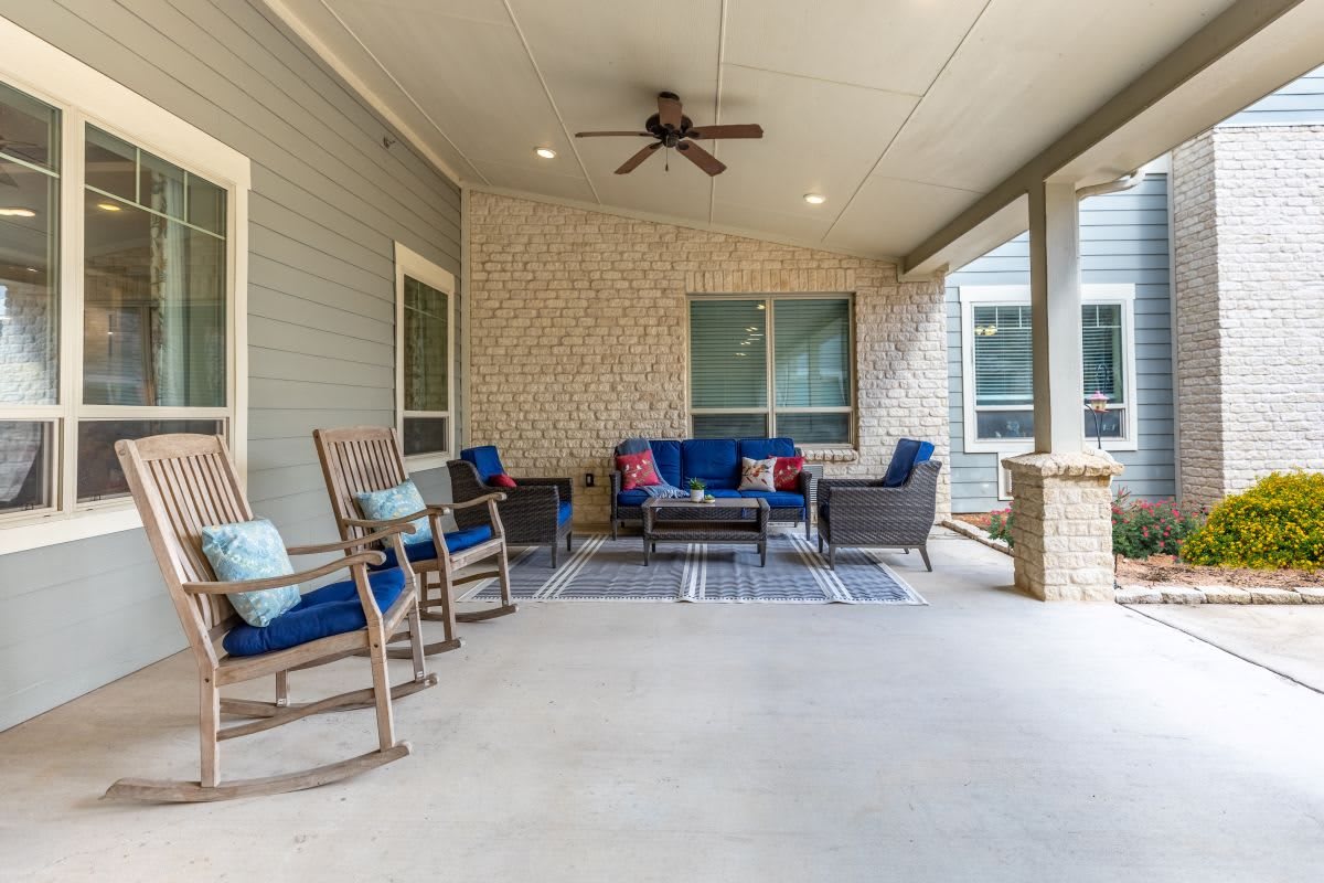 A cozy outdoor patio with comfortable seating and a ceiling fan.