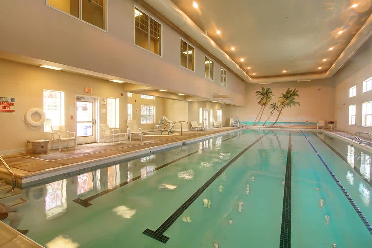 A serene indoor swimming pool area with ample lighting and comfortable seating.