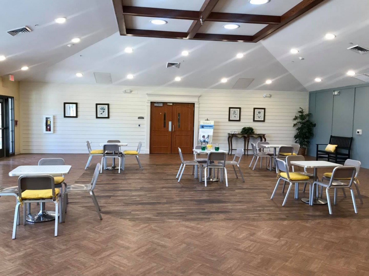 A spacious and bright cafe interior with neatly arranged tables and chairs on a wooden floor.