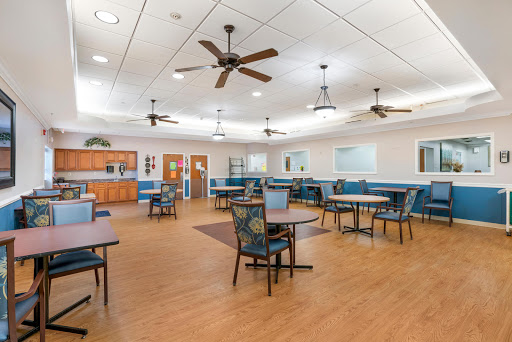 A spacious and well-lit dining area featuring tables and chairs, with ceiling fans for comfort.