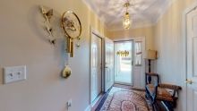 A bright hallway with a clock, carpet, and decorative lighting.