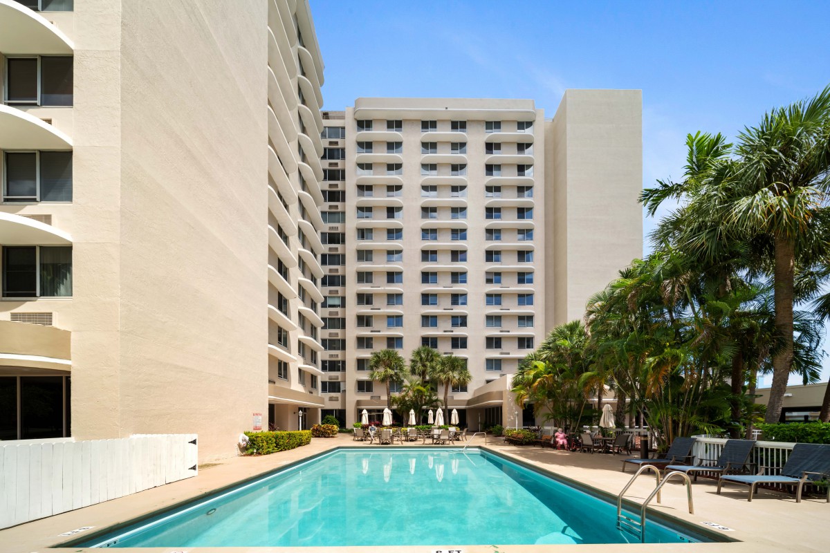 High-rise apartment building with a swimming pool and palm trees.