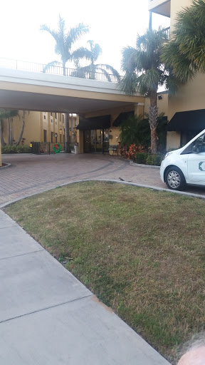 A view of the entrance to a hotel, featuring a neatly maintained parking area and a white vehicle.