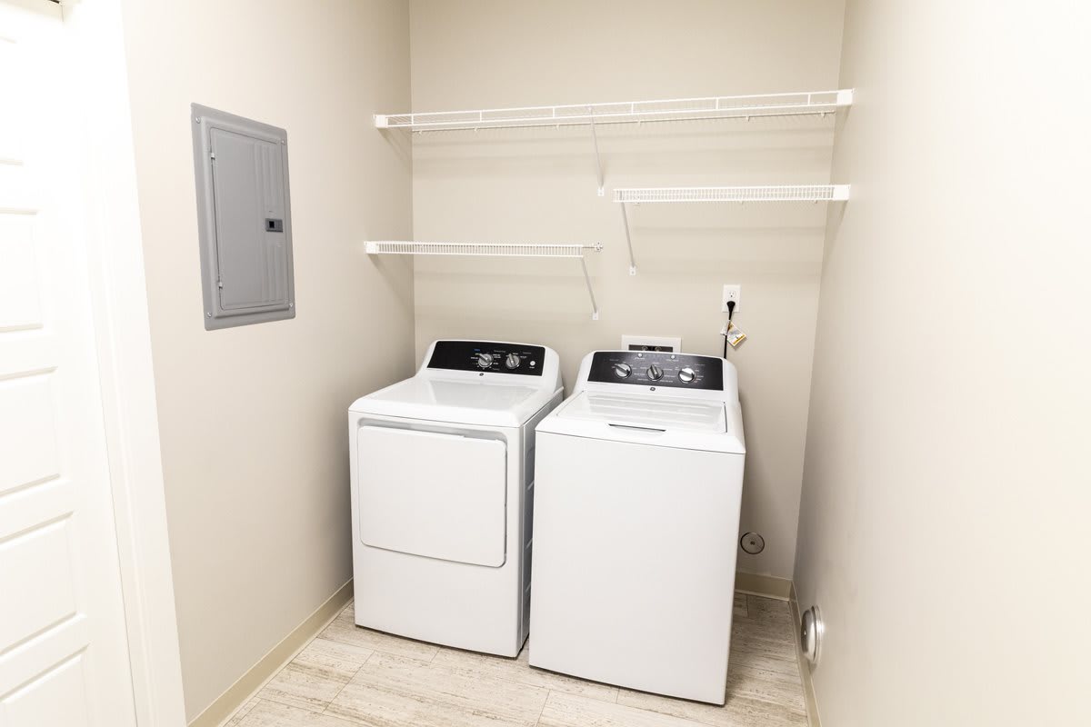 A laundry room featuring a washing machine and dryer with overhead shelving.