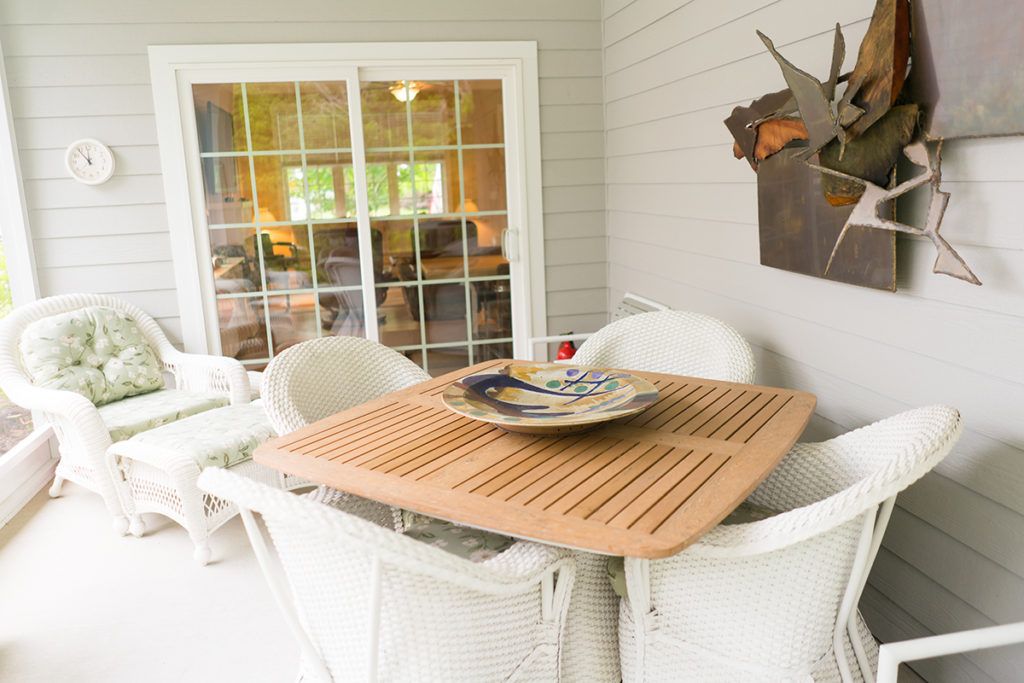 Cozy outdoor patio with a wooden table and white chairs, perfect for relaxation.