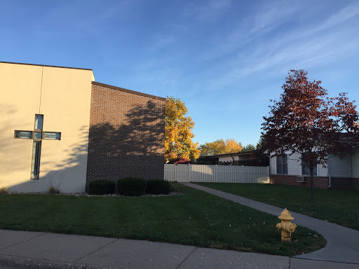 A view of a residential or commercial building with autumn trees in the foreground under a clear blue sky.