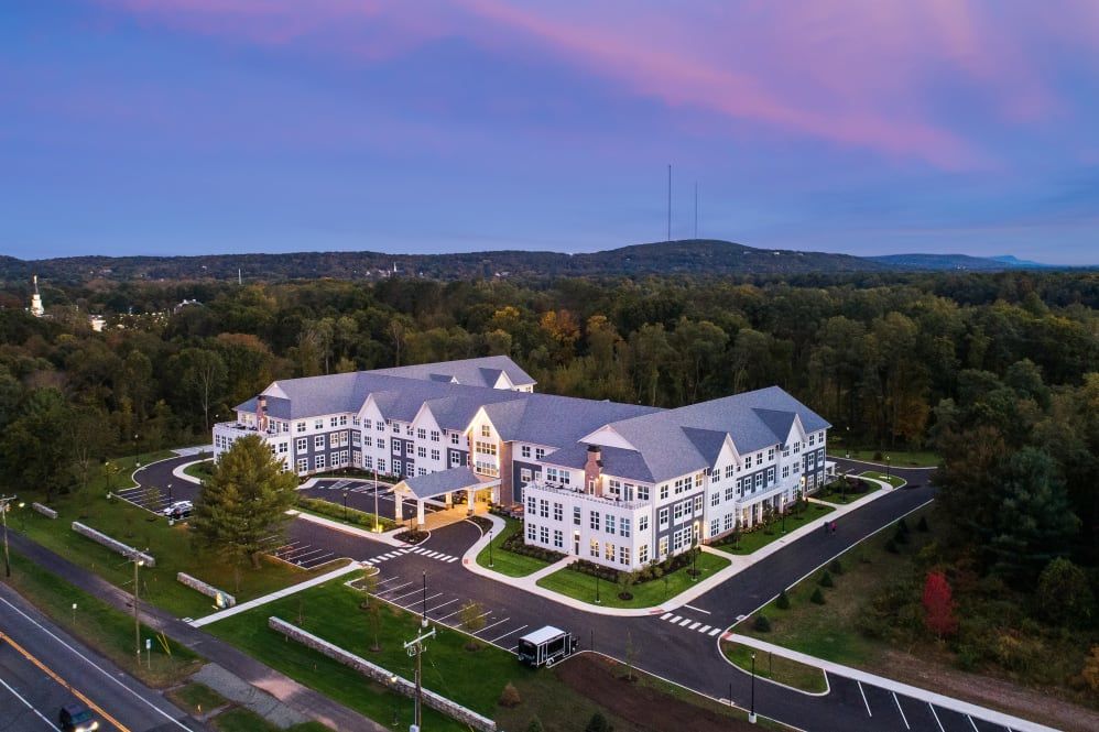 A beautiful aerial view of a large residential building surrounded by greenery, captured at sunset.