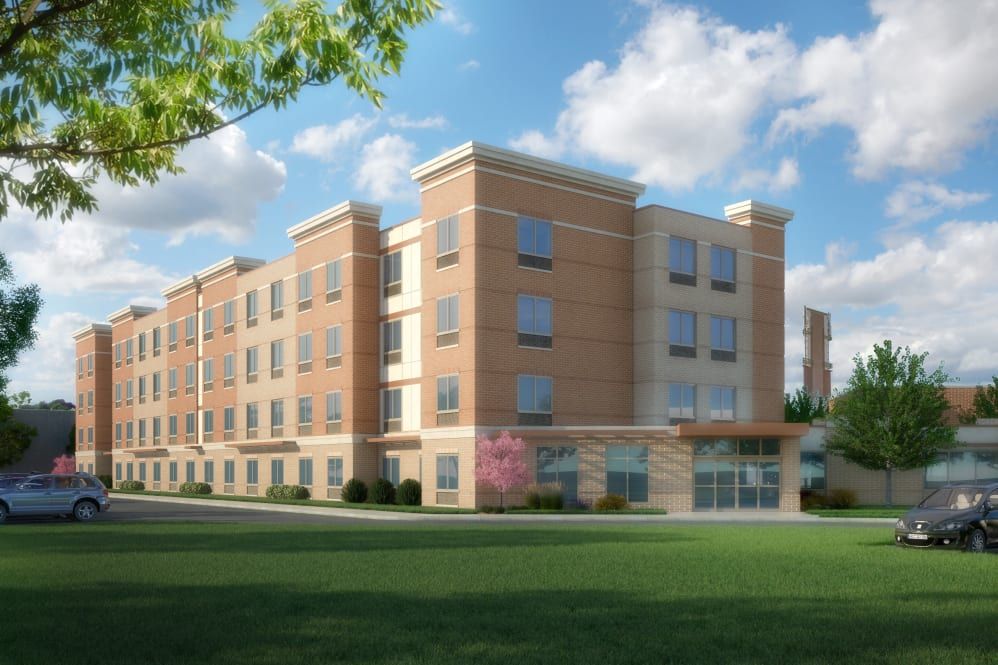 A modern apartment building with a brick facade under a clear blue sky.