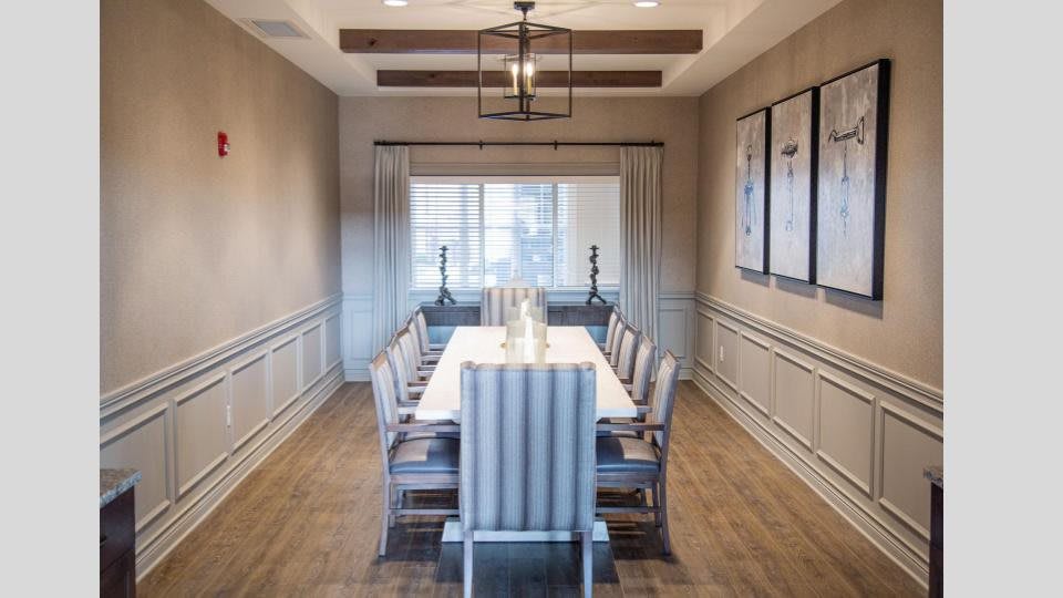 A modern dining room with elegant decor and a long table surrounded by chairs.
