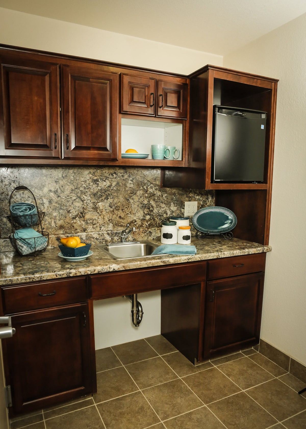 A compact kitchen space featuring wooden cabinets, a granite countertop, and various kitchen appliances.