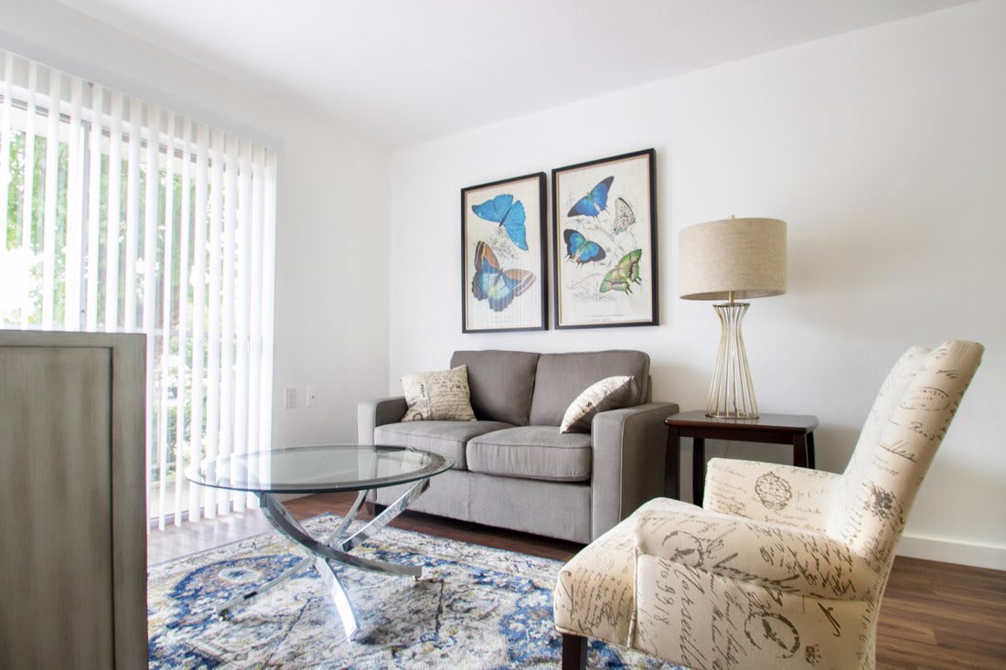 A modern living room with a gray sofa and butterfly artwork on the wall.