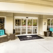 Entrance of a building with glass doors and outdoor seating.