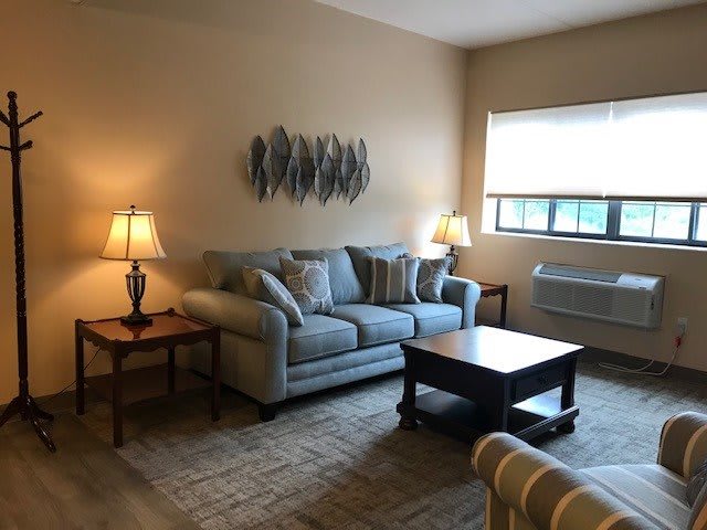 A cozy living room with a sofa, coffee table, and warm lighting from lamps.