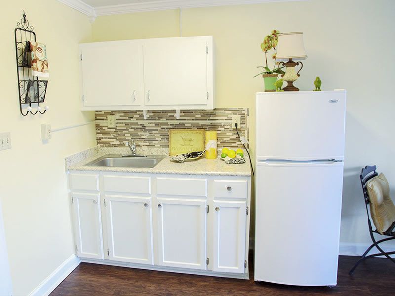 A compact kitchen with white cabinets and a refrigerator.