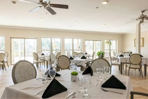 A beautifully arranged dining area featuring elegant tables set for a meal with napkins and glassware, bathed in natural light.