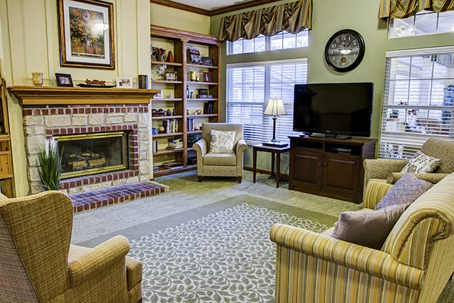A cozy living room with a fireplace, bookshelves, and a television.