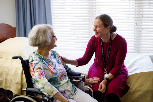 A caregiver engages in a warm conversation with an elderly woman in a cozy indoor setting.