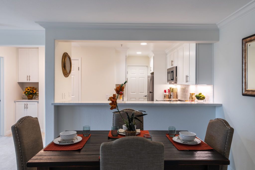 A modern kitchen with an open layout dining area, featuring a minimalist table setting and contemporary design.