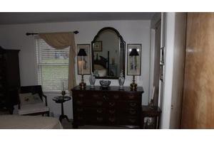 A well-decorated bedroom features a dresser with a mirror and lamps.