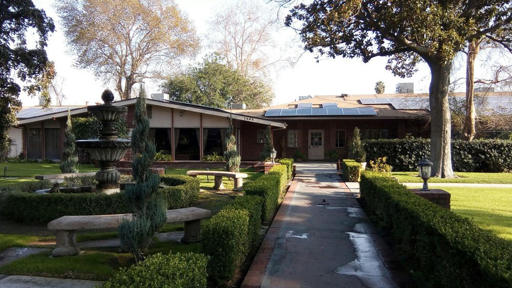 A scenic view of a house surrounded by a neatly landscaped garden with a pathway leading to the entrance.