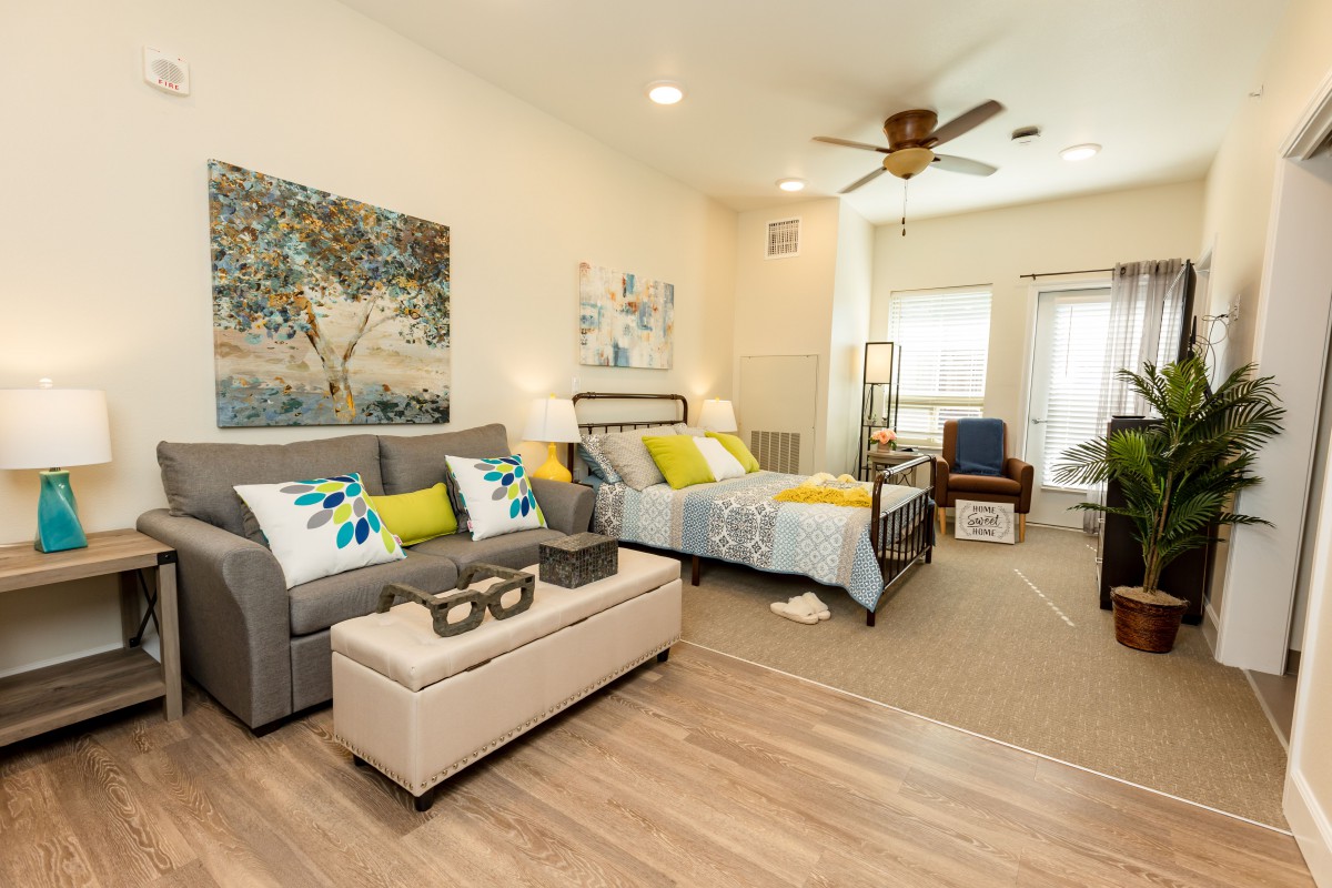 A modern and cozy combined bedroom and living area, featuring a comfortable sofa and bed with vibrant decor.