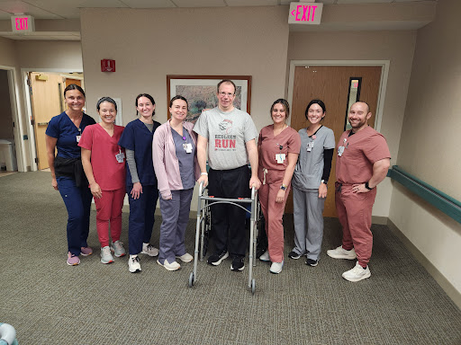 A group of healthcare professionals proudly supporting a patient in rehabilitation.