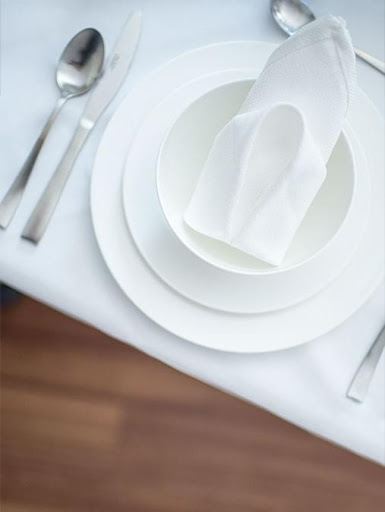An elegant table setting featuring white plates, a folded napkin, and cutlery arranged neatly.