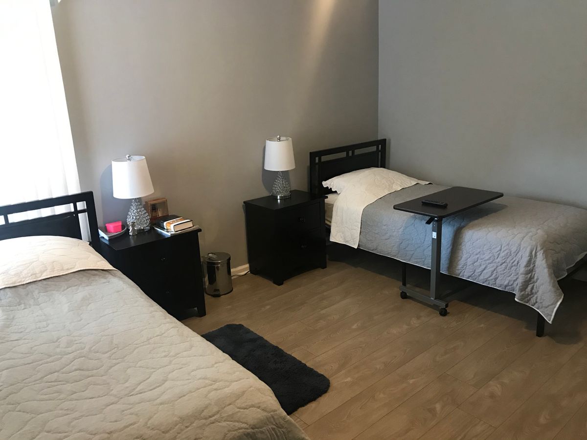 A modern bedroom with two single beds, nightstands, and lamps.
