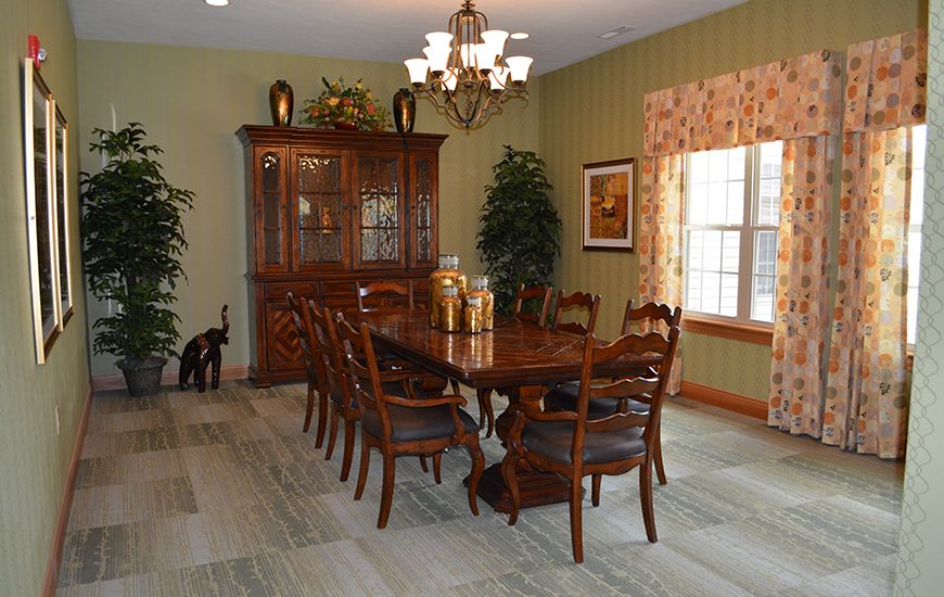 A well-furnished dining room with a large wooden table, chairs, and a chandelier overhead.